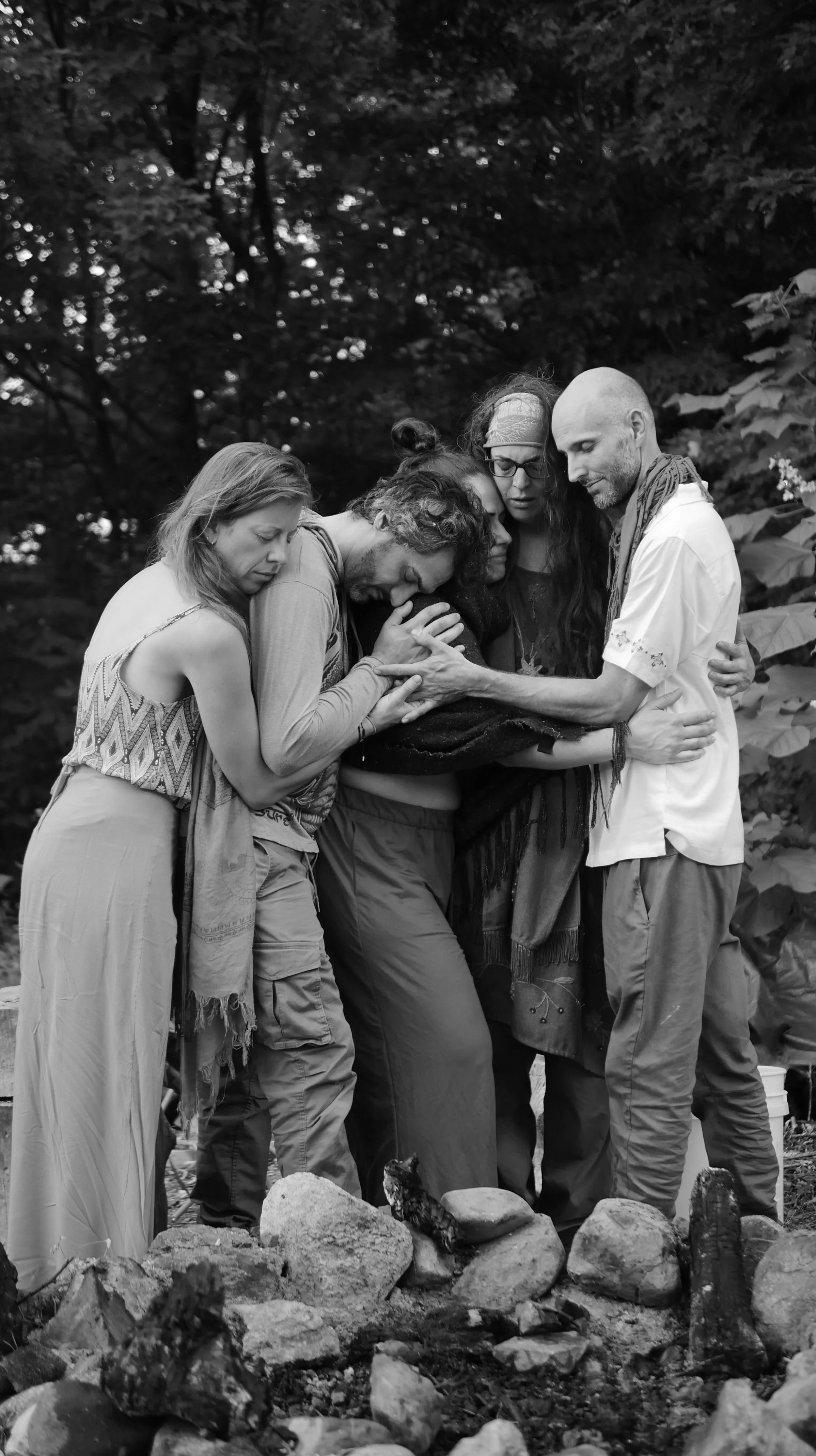 Groupe de cinq personnes en méditation dans un environnement naturel, en noir et blanc.